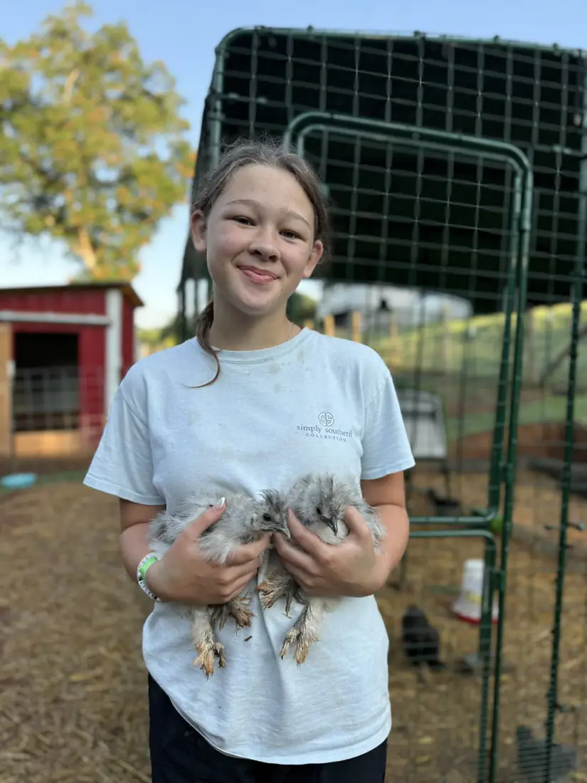 A visitor smiling while holding a hen