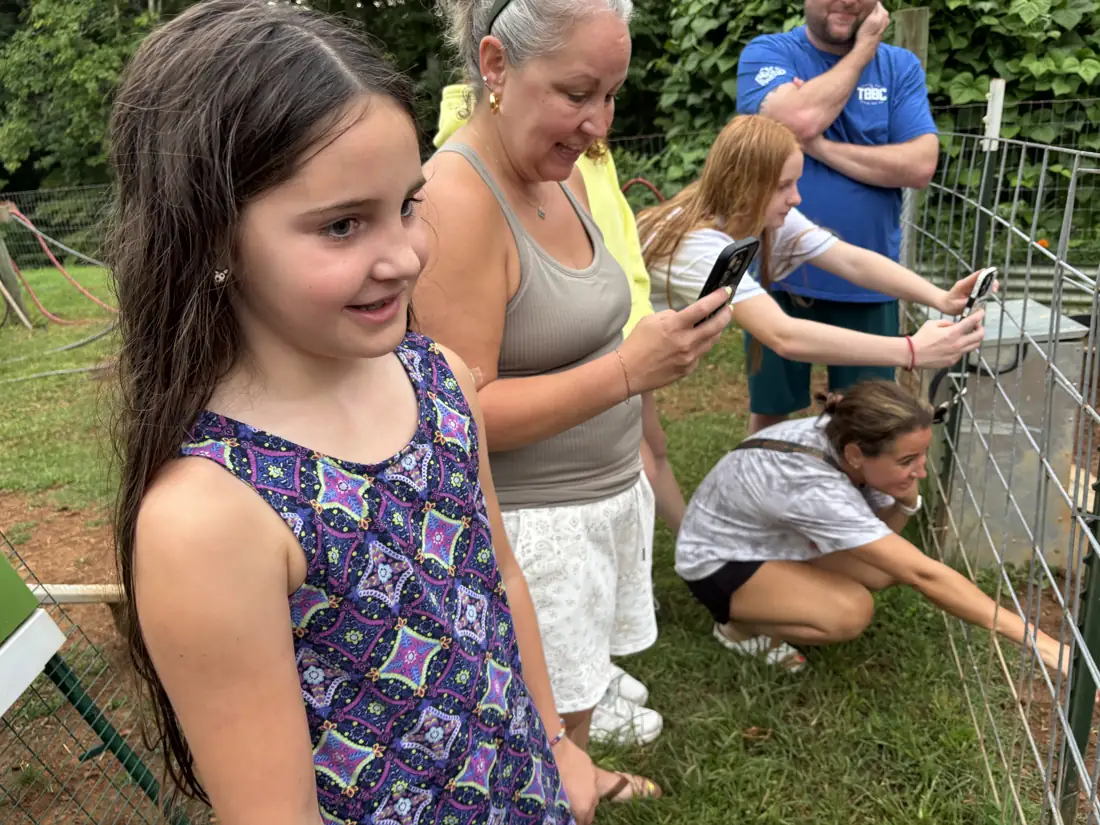 A girl and two women looking into the chicken coop