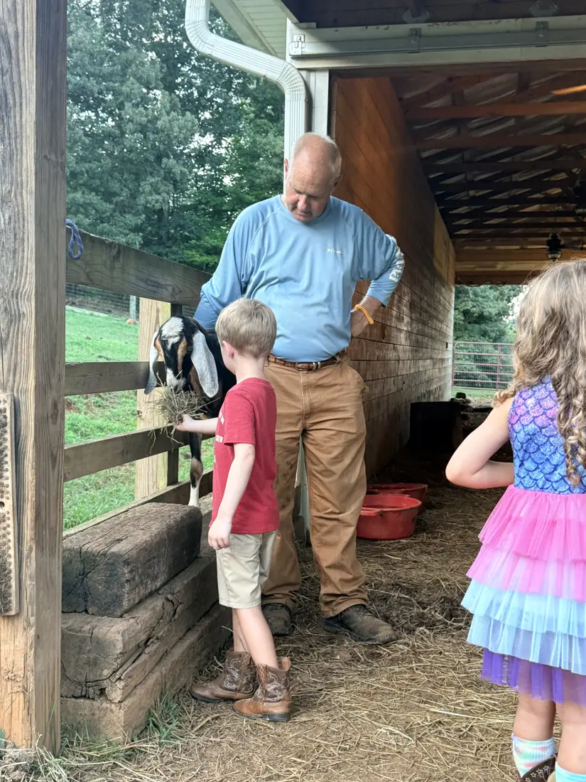 A man showing two children around inside the barn