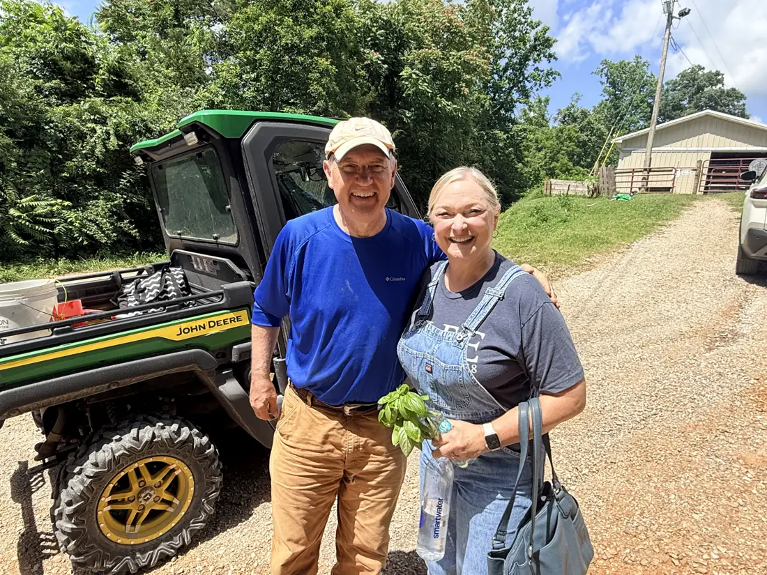 Two visitors by the farm Gator holding greens for the animals